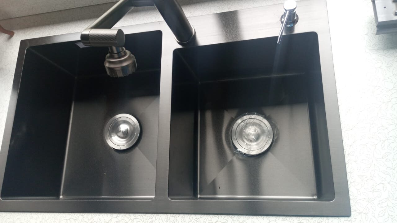 Fregadero de cocina negro sobre un mostrador de madera.